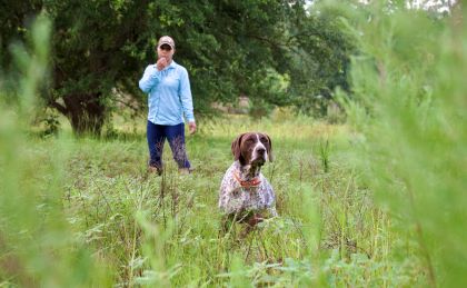 Manda standing with  dog in grassy field